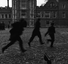 three people are running in front of an old building with a clock tower on it