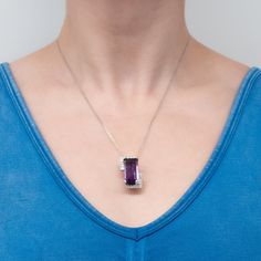 This stunning 14K white gold pendant is centered with one (1) cut-cornered rectangular step cut natural amethyst set into a four-prong setting. The amethyst is bordered with eighteen (18), bead set, round brilliant cut diamonds. The pendant measures 27.0mm X 16.9mm X 13.3mm and is suspended from a 14K white gold cable link style neck chain measuring 18 inches in length. Purple Rectangular Jewelry For Formal Occasions, Formal Purple Jewelry With Polished Finish, Elegant Purple Necklace, Elegant Purple Jewelry With Polished Finish, Formal Rectangular Purple Jewelry, Formal Purple Necklace With Polished Finish, Elegant Emerald Cut Purple Jewelry, Formal Amethyst Baguette Cut Jewelry, Formal Baguette Cut Amethyst Jewelry