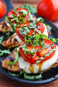 grilled chicken with tomatoes and greens on a black plate