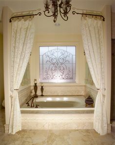 a bath tub sitting under a window next to a chandelier