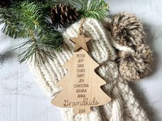 a wooden ornament hanging from a christmas tree on a knitted blanket with pine cones