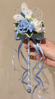 a hand holding a blue and white corsage