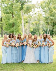 a group of women standing next to each other holding bouquets in front of trees