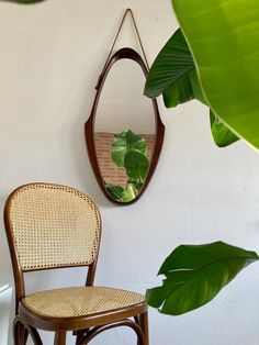 a wooden chair sitting next to a wall with a mirror hanging on it's side