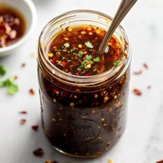 a glass jar filled with chili sauce and garnished with cilantro