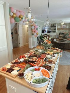 a table filled with lots of food on top of a wooden counter next to balloons