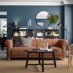 a living room filled with furniture and a round mirror on the wall over a coffee table