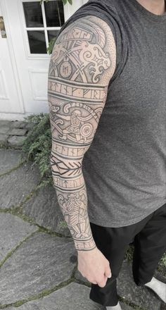 a man with a large tattoo on his arm and shoulder is standing in front of a white door