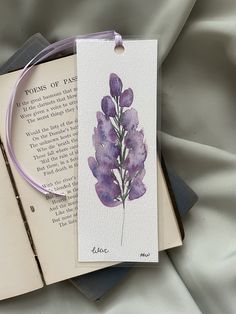 an open book with a purple flower on it and a string attached to the cover