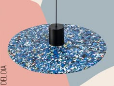 a blue and pink circular table with a black pole in the middle, surrounded by confetti sprinkles