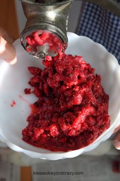 a person pouring red food into a white bowl