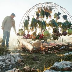 a man standing next to a pile of fruit on top of a grass covered field