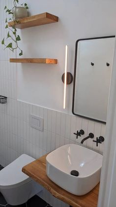 a bathroom with a sink, toilet and shelves on the wall above it's mirror