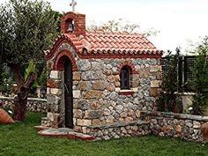 a small church made out of rocks in the grass