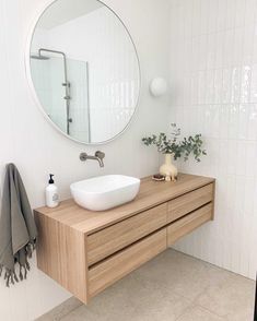 a bathroom sink sitting under a round mirror