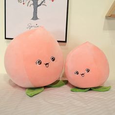 two large stuffed peaches sitting on top of a bed next to a framed tree