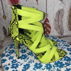 a pair of neon yellow high heel shoes on top of a blue and white flowered surface