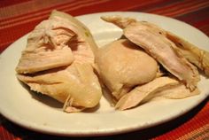 three pieces of chicken on a white plate with red table cloth in the back ground