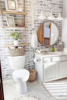 a white toilet sitting next to a bathroom sink under a round mirror on top of a wooden shelf