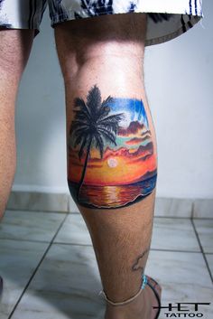 a man with a sunset and palm tree tattoo on his leg