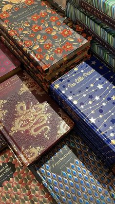 many different colored books are stacked on top of each other, all with gold and blue designs