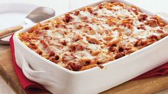 a casserole dish with meat and cheese in it on a wooden cutting board