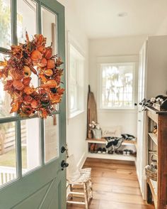 a green door with a wreath hanging on it's side in front of a kitchen