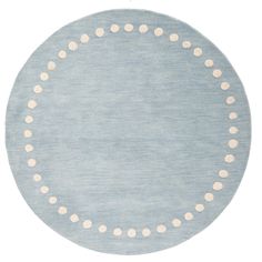 a round rug with white dots on it in light blue and beige colors, isolated against a white background