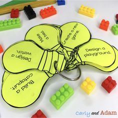 a bunch of legos with name tags attached to them on a white table next to pencils and markers