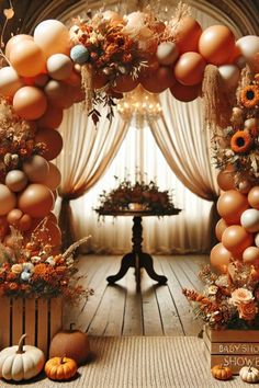 an orange and white balloon arch decorated with sunflowers, pumpkins and flowers