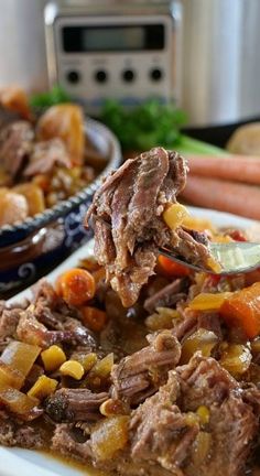 a spoon full of beef and carrots on top of a plate next to an instant pot roast