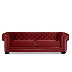 a red couch with buttons on the back and arms, sitting in front of a white background