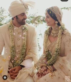 a man and woman dressed in wedding attire sitting next to each other on the ground