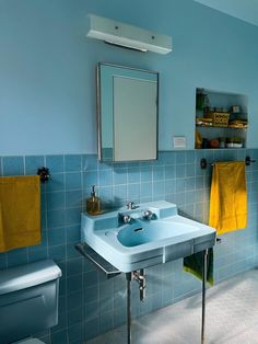 a bathroom with blue tiles and yellow towels