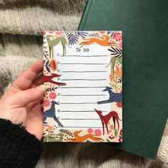 a hand holding a notepad with animals on it and to do list in the middle