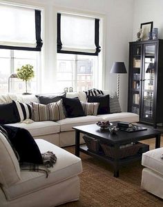 a living room filled with white couches and black pillows on top of it's covers