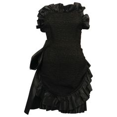 Dramatic, jet-black textured dress with satin ruffled trim and large bow designed by Yves Saint Laurent dating to the 1980's. Fully internal corset with boning at bodice. Labeled a French size 38. Approximate measurements: bust 32", waist (inner waistband) 25.5" , hips 33" (give up to 36") and overall length 26". Fabric content: 72% acetate, 28% viscose and lining 100% Cotton. Made in France. Very good condition. Yves Saint Laurent Couture Dresses, Ysl Vintage Dress, Vintage Ysl Dress, Vintage Saint Laurent Dress, Saint Laurent Black Dress, Vintage Mini Dress, Vintage Mini Dresses, Dress With Ruffles, Black Strapless Dress