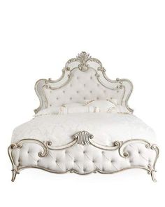 a white bed with an ornate headboard and foot board