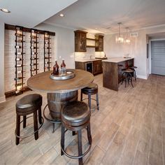 a kitchen and dining room with wine racks on the wall behind the bar stools