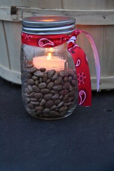 a jar filled with coffee beans and a lit candle