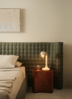 a bed sitting next to a night stand with a lamp on it's side