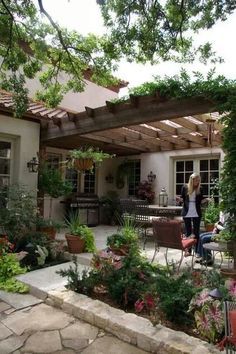 a woman standing in the middle of a patio with potted plants on either side