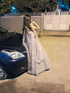 a woman standing next to a parked car