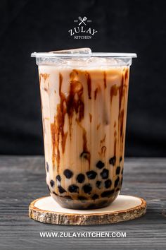 an iced drink with chocolate and caramel in a plastic cup on a wooden coaster