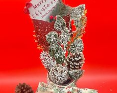 a christmas decoration with pine cones and candy canes on a red tablecloth background