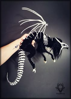 a hand holding a stuffed animal that looks like a dragon with wings and claws on it's head