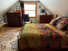 a bed room with a neatly made bed next to a window and a rug on the floor