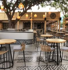 an outdoor dining area with tables and chairs, lights hanging from the ceiling and trees in the background