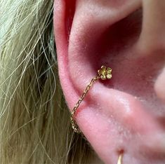 a close up view of a person's ear with a gold flower on it