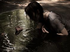 a woman is in the water with her hand up to her face as she reaches for something